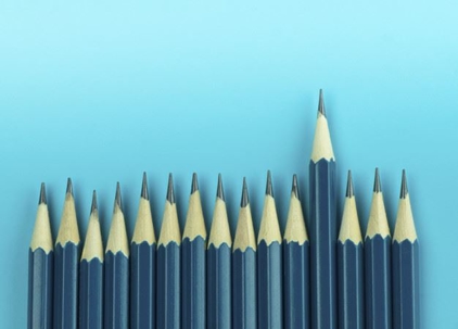 One sharpened pencil standing out from a row of other pencils