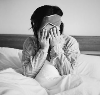 Woman in bed covering her eyes