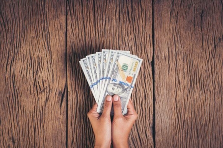 hands holding hundred dollar bills