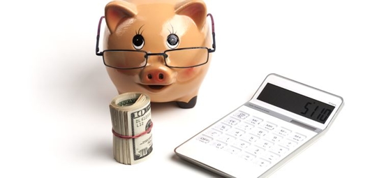 piggy bank next to roll of money and calculator
